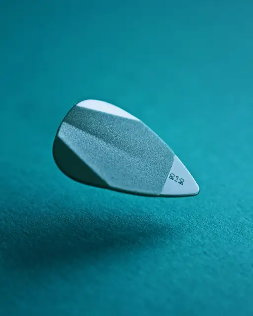 A detailed close-up of a levitating guitar pick against a teal background, showcasing texture.